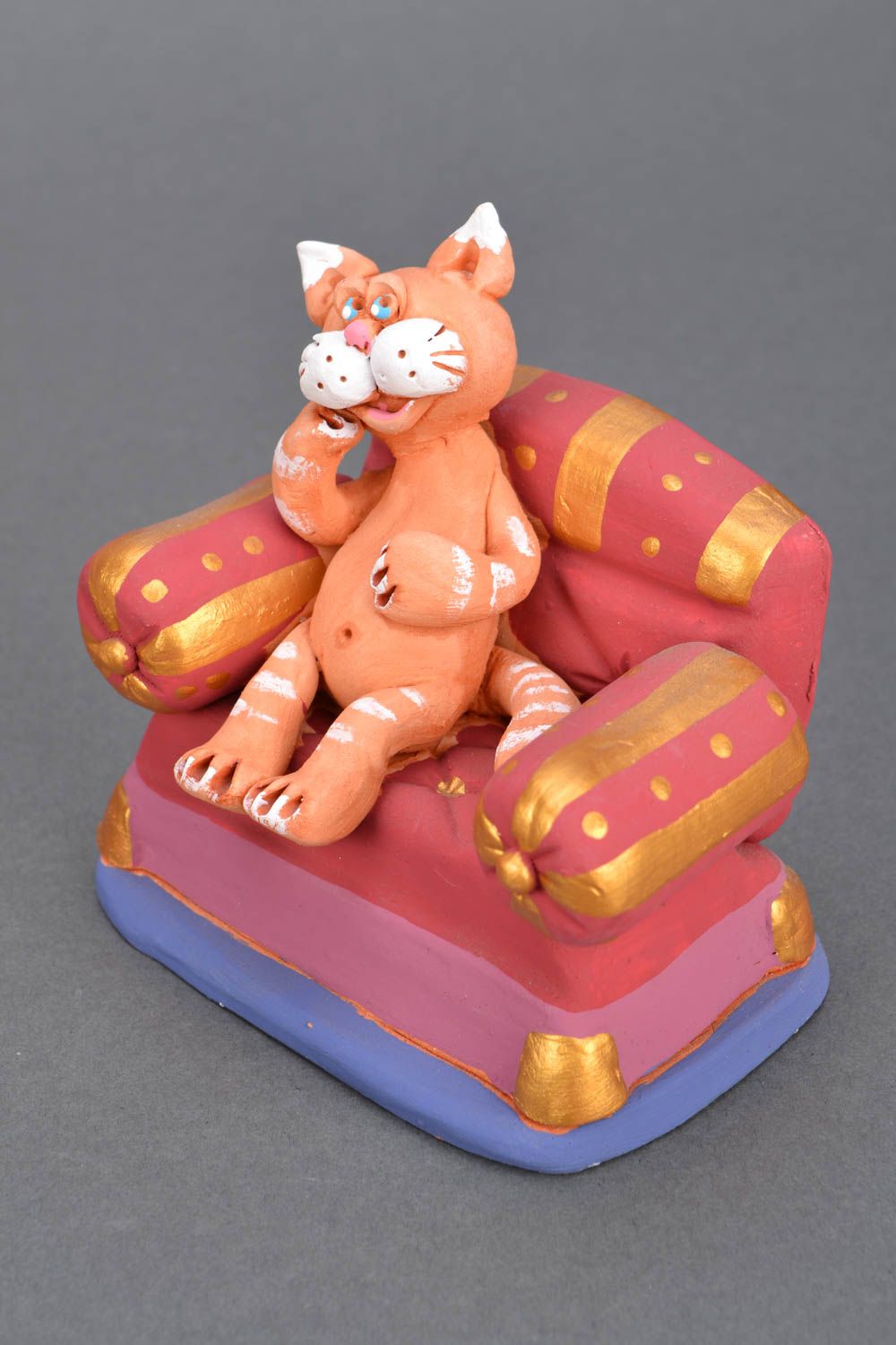 Funny figure in the form of a red cat on the sofa.