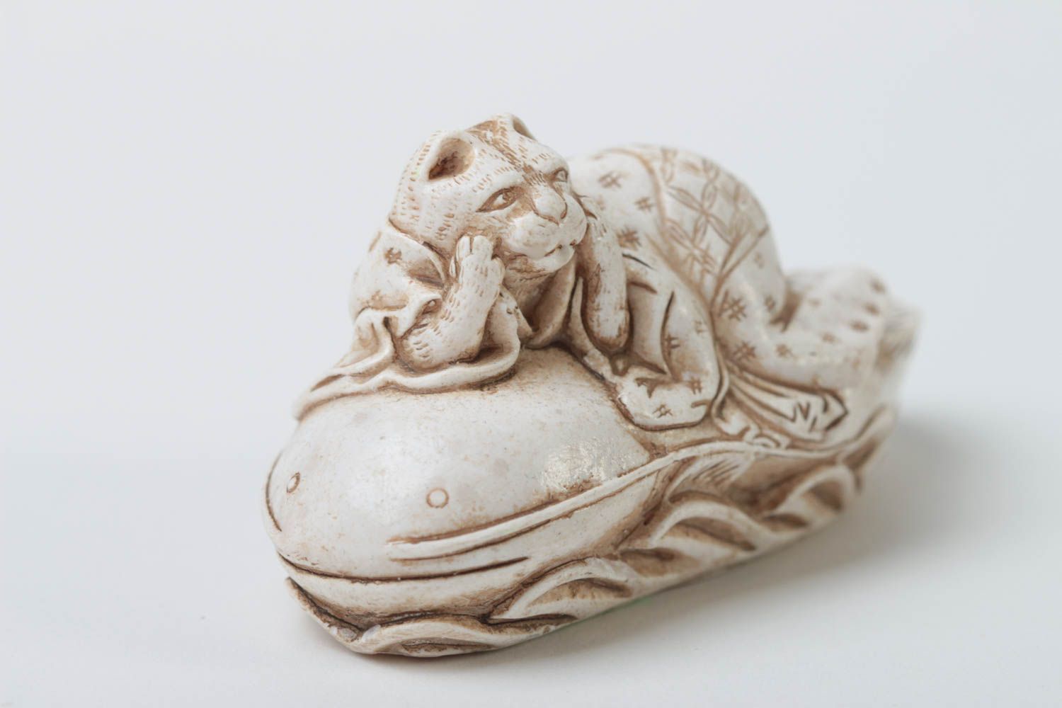 Figurine in the style of feng shui cat on a catfish.