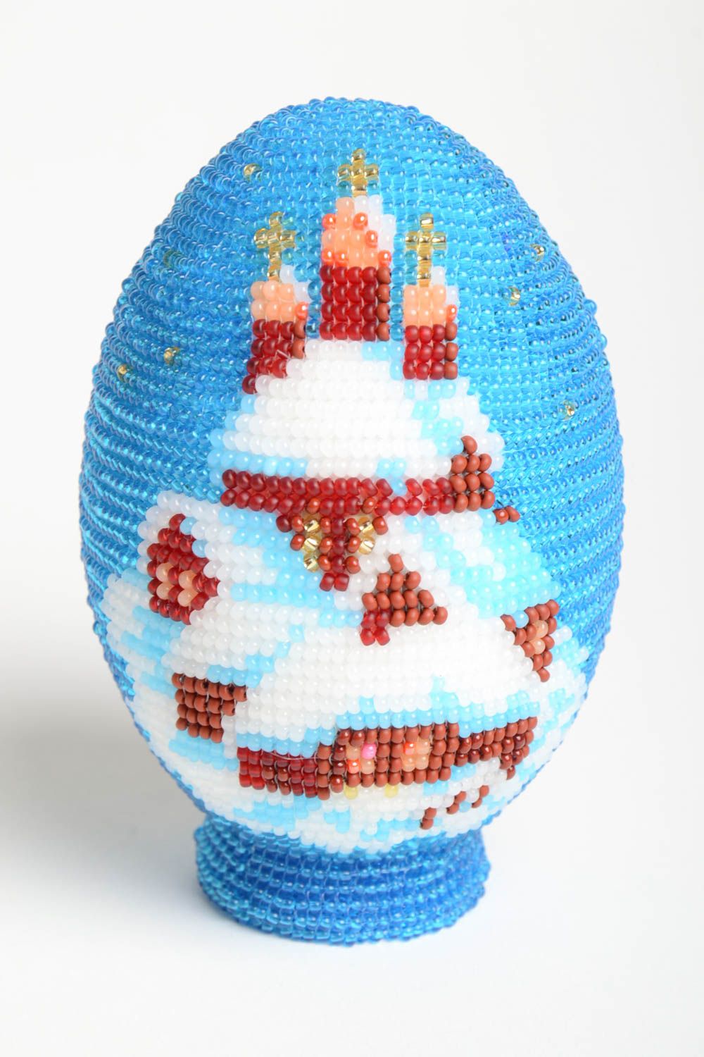 Statue on a wooden base with a beaded image of the winter church.